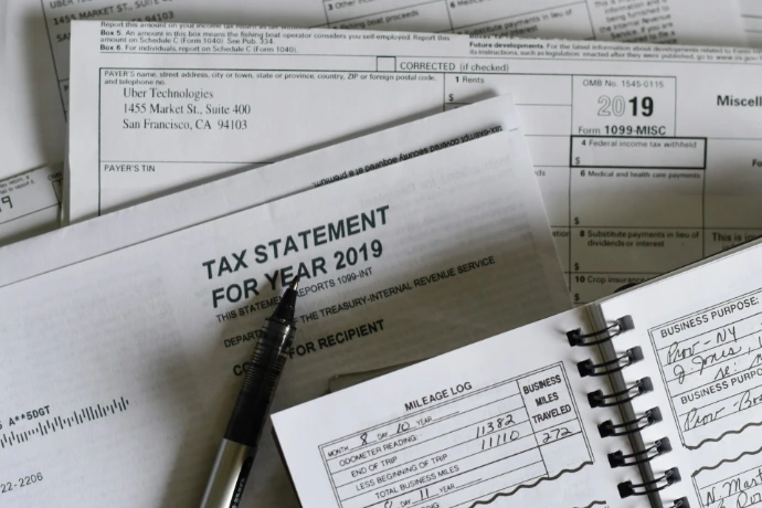 A pen resting on 2019 tax forms and a mileage log book